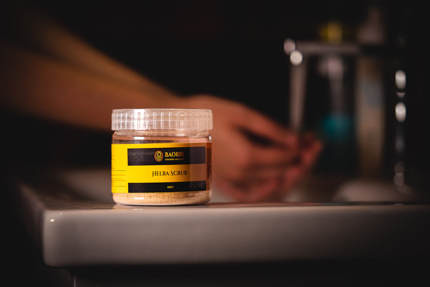 Body scrub on a sink washing hands in the background