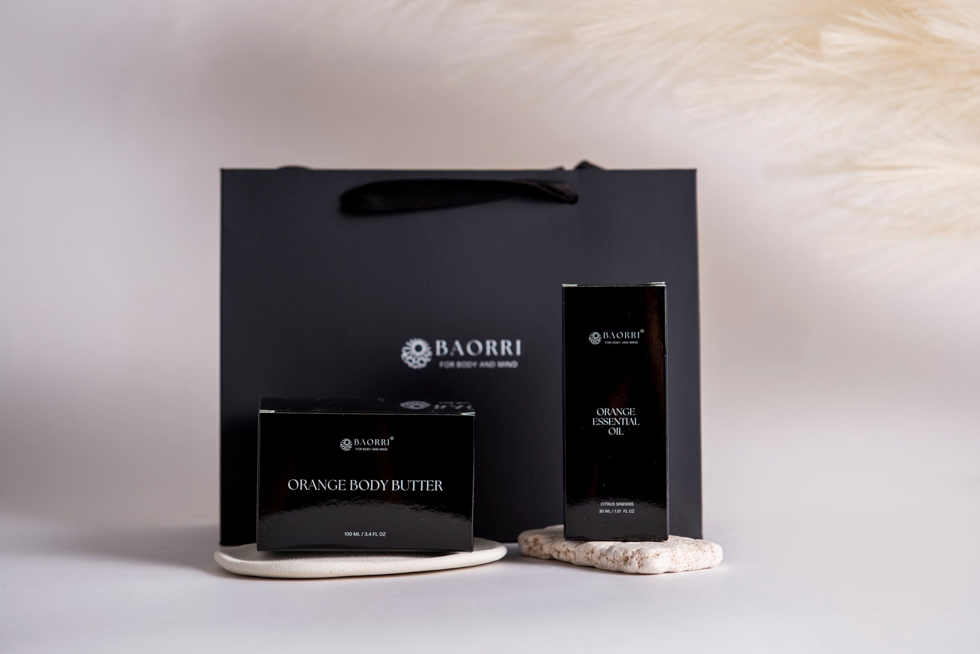 orange body butter and orange essential oil in a grey background